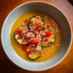Bowl of creamy acorn squash soup garnished with herbs