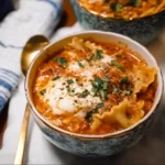 Bowl of creamy lasagna soup topped with cheese and herbs