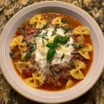 Bowl of homemade lasagna soup with bow tie pasta topped with cheese and herbs