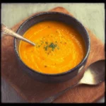 Bowl of spiced carrot ginger soup garnished with herbs