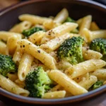 Creamy broccoli cheese pasta dish garnished with fresh herbs.