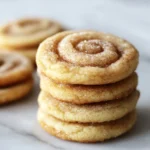 Freshly baked cinnamon roll sugar cookies topped with frosting and cinnamon