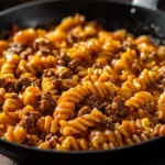 Bowl of cheesy taco pasta topped with cheese and fresh herbs