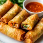 Crispy Chinese egg rolls filled with vegetables and meats on a plate.