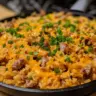 Easy cheesy sausage and rice skillet dish served in a pan with colorful ingredients