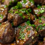 Garlic butter steak bites served on a plate with herbs and seasoning.