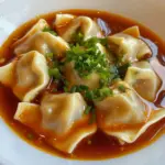 Plate of homemade tofu and chive wontons garnished with fresh herbs