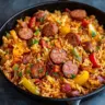 Sausage and rice skillet dish with colorful vegetables in a frying pan