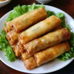 Plate of crispy Vietnamese Egg Rolls (Chả Giò) with dipping sauce and vegetables