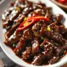 Plate of crispy Mongolian beef with rice and vegetables.