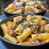 Creamy Cajun steak tips served with cheesy rigatoni parmesan on a plate.