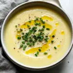 Bowl of creamy potato leek soup garnished with fresh herbs