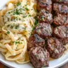 Garlic Butter Steak Bites served with creamy Alfredo pasta on a plate