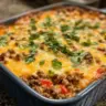 Keto Ground Beef Casserole topped with cheese and herbs in a baking dish