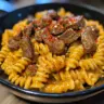 One-pot sweet and spicy buffalo steak pasta dish garnished with herbs