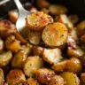 Bowl of crispy Parmesan Roasted Potatoes garnished with fresh herbs