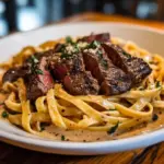 Savory steak pasta dish garnished with herbs and served in a bowl