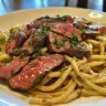Delicious simple steak pasta dish with fresh ingredients served on a plate.