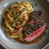 Delicious plate of steak pasta with herbs and spices.