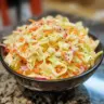 Bowl of creamy coleslaw with cabbage and carrots on a table