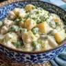 Creamy green bean potato salad in a dish, garnished with herbs.