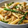Creamy mushroom asparagus chicken penne served in a bowl with fresh herbs