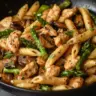 Creamy mushroom and asparagus chicken penne dish served in a bowl