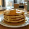 Stack of light and fluffy pancakes topped with fresh berries and syrup