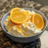 Greek yogurt orange fluff dessert in a bowl garnished with orange slices