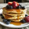 Fluffy Greek Yogurt Pancakes stacked on a plate with syrup and berries