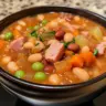 Bowl of hearty ham and bean soup garnished with herbs