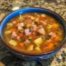 Bowl of hearty ham soup with vegetables and herbs