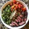 Mediterranean steak bowl topped with fresh veggies and herbs
