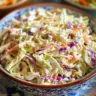 Bowl of old fashioned coleslaw with vinegar dressing and fresh vegetables