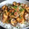 Parmesan-Garlic Mushroom Chicken served on a plate with herbs and garlic cloves.