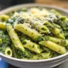 Bowl of pasta with creamy spinach sauce garnished with parmesan cheese