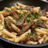Delicious plate of savory skirt steak pasta with herbs and sauce.
