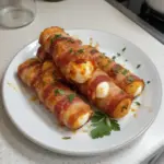 Bacon-wrapped mozzarella sticks served on a plate, perfect appetizer.