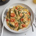 Baked Feta Orzo topped with herbs and feta cheese served in a bowl.
