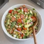 Chickpea salad with fresh vegetables and dressing in a bowl