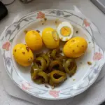 Spicy Cowboy Candy Pickled Eggs in a jar with vibrant colors and spices.