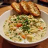 Crockpot creamy chicken noodle soup in a bowl with herbs and vegetables
