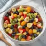 Delicious fruit salad drizzled with honey lime dressing, served in a bowl.
