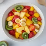 Easter Fruit Salad topped with Peach Pie Filling in a colorful bowl
