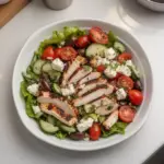 Fresh Greek Salad with Chicken topped with olives, feta cheese, and colorful veggies.