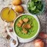 A bowl of delicious frozen pea soup garnished with herbs