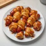 Plate of glazed pigs in a blanket for a tasty appetizer