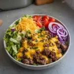 High-Protein Cheeseburger Bowl filled with beef, vegetables, and toppings