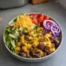 High-Protein Cheeseburger Bowl filled with beef, vegetables, and toppings