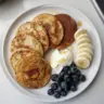Stack of high protein pancakes topped with fresh berries and syrup